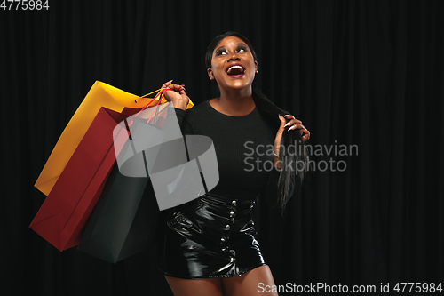 Image of Young woman in dress shopping on black background