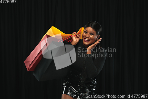 Image of Young woman in dress shopping on black background