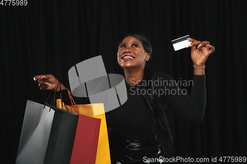 Image of Young woman in dress shopping on black background