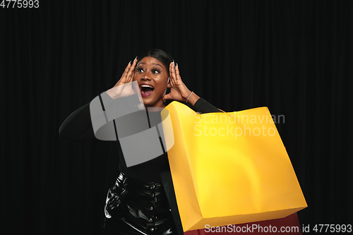 Image of Young woman in dress shopping on black background