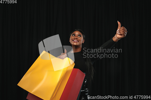 Image of Young woman in dress shopping on black background