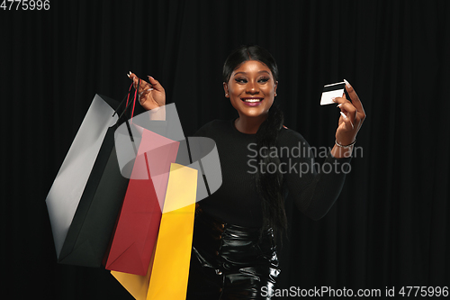 Image of Young woman in dress shopping on black background