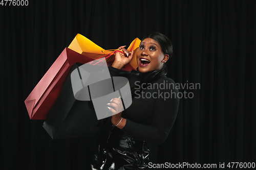 Image of Young woman in dress shopping on black background