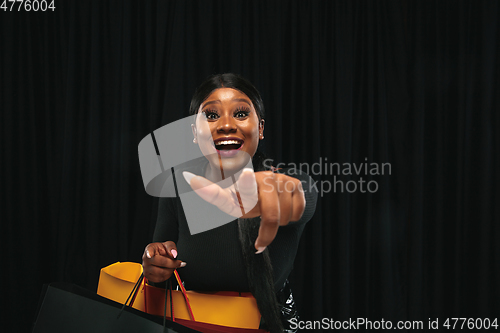 Image of Young woman in dress shopping on black background