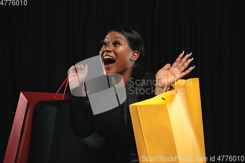 Image of Young woman in dress shopping on black background