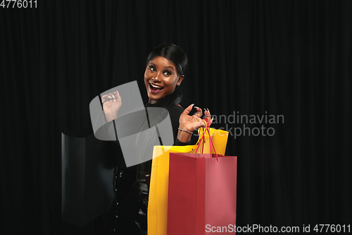 Image of Young woman in dress shopping on black background