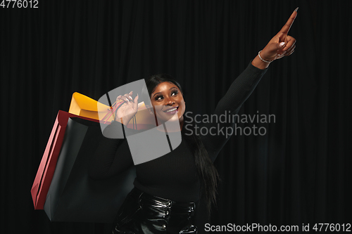 Image of Young woman in dress shopping on black background