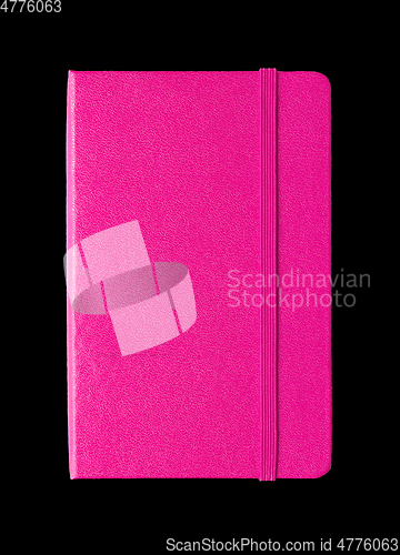 Image of Magenta pink closed notebook isolated on black