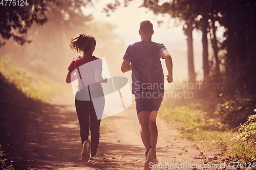 Image of couple enjoying in a healthy lifestyle while jogging on a country road