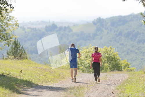 Image of couple enjoying in a healthy lifestyle while jogging on a country road