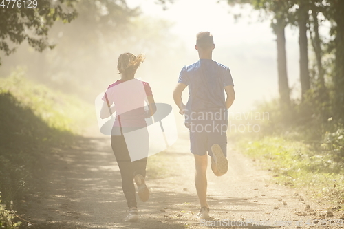 Image of couple enjoying in a healthy lifestyle while jogging on a country road