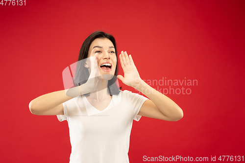 Image of Caucasian young woman\'s half-length portrait on red background