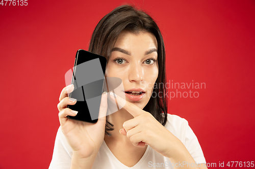 Image of Caucasian young woman\'s half-length portrait on red background