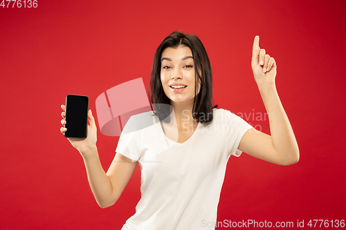 Image of Caucasian young woman\'s half-length portrait on red background