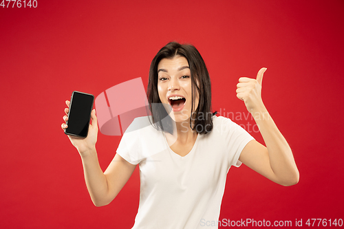 Image of Caucasian young woman\'s half-length portrait on red background