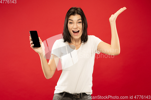 Image of Caucasian young woman\'s half-length portrait on red background