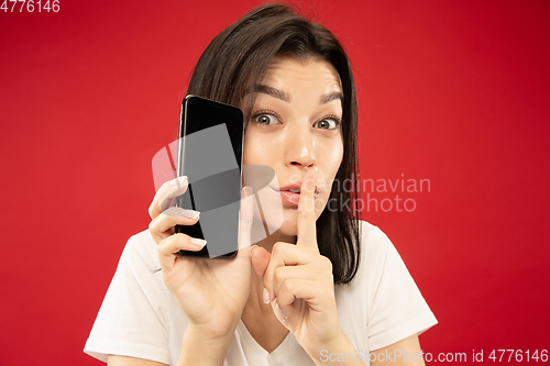 Image of Caucasian young woman\'s half-length portrait on red background
