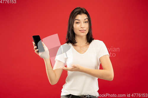 Image of Caucasian young woman\'s half-length portrait on red background