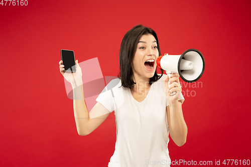 Image of Caucasian young woman\'s half-length portrait on red background