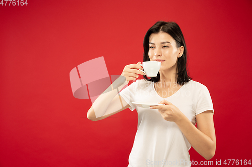 Image of Caucasian young woman\'s half-length portrait on red background