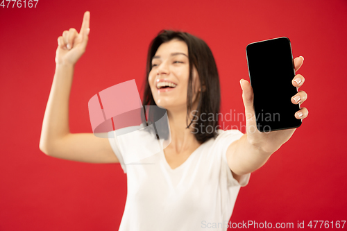 Image of Caucasian young woman\'s half-length portrait on red background