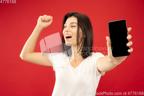 Image of Caucasian young woman\'s half-length portrait on red background