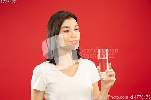 Image of Caucasian young woman\'s half-length portrait on red background