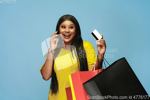 Image of Young woman in dress shopping on blue background