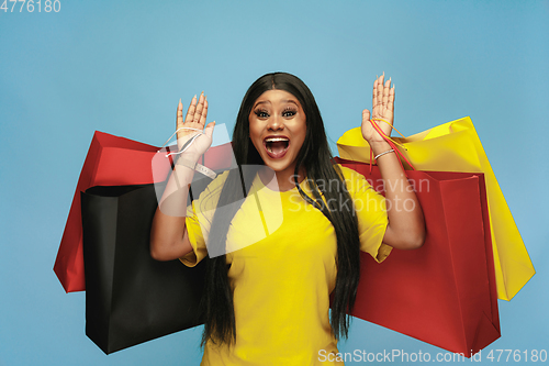 Image of Young woman in dress shopping on blue background