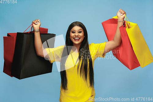 Image of Young woman in dress shopping on blue background