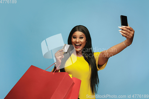Image of Young woman in dress shopping on blue background
