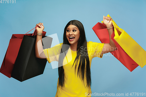 Image of Young woman in dress shopping on blue background