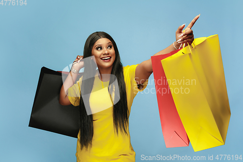 Image of Young woman in dress shopping on blue background