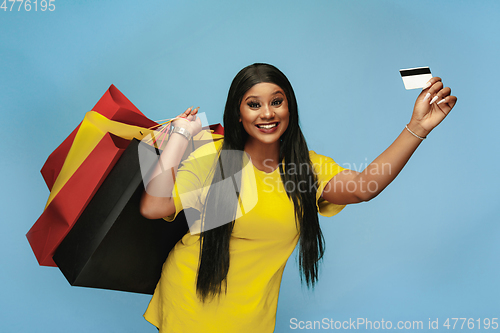 Image of Young woman in dress shopping on blue background