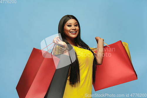 Image of Young woman in dress shopping on blue background