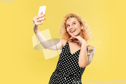 Image of Caucasian young woman\'s half-length portrait on yellow background