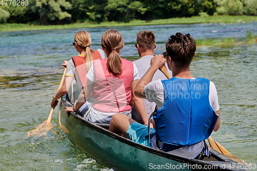 Image of Group adventurous explorer friends are canoeing in a wild river