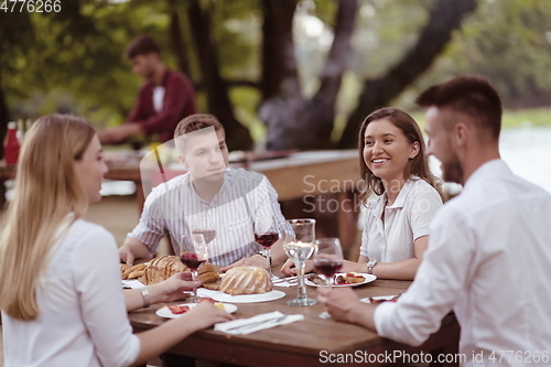 Image of friends having picnic french dinner party outdoor during summer holiday