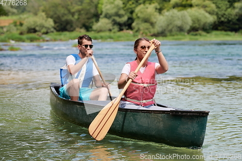 Image of friends are canoeing in a wild river