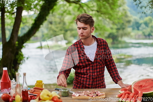 Image of man putting spices on raw meat for barbecue