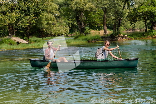 Image of friends are canoeing in a wild river