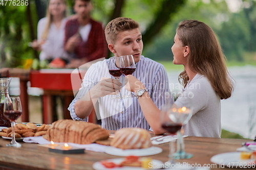 Image of friends having picnic french dinner party outdoor during summer holidayfriends having picnic french dinner party outdoor during summer holiday