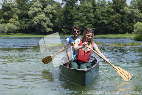 Image of friends are canoeing in a wild river