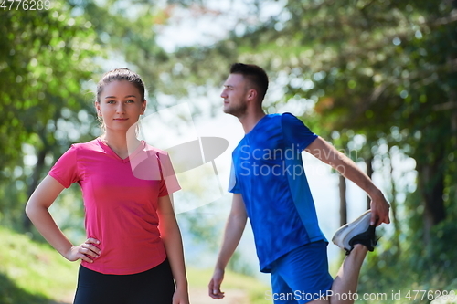 Image of couple enjoying in a healthy lifestyle warming up and stretching before jogging