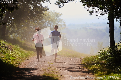 Image of couple enjoying in a healthy lifestyle while jogging on a country road