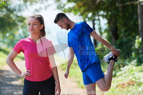 Image of couple enjoying in a healthy lifestyle warming up and stretching before jogging