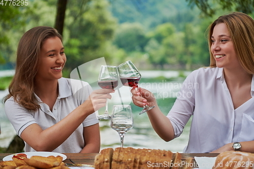 Image of girlfriends having picnic french dinner party outdoor