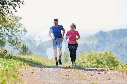Image of couple enjoying in a healthy lifestyle while jogging on a country road