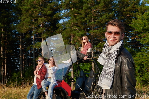 Image of group young happy people enjoying beautiful sunny day while driving a off road buggy car