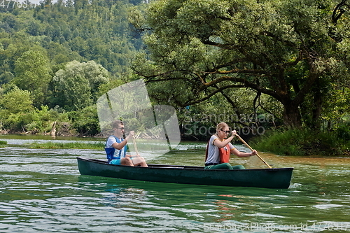 Image of friends are canoeing in a wild river